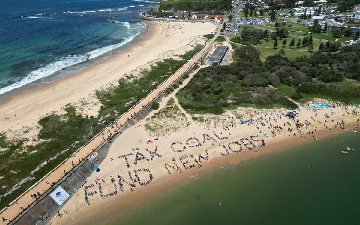 Human sign on Newcastle beach reads TAX COAL FUND NEW JOBS