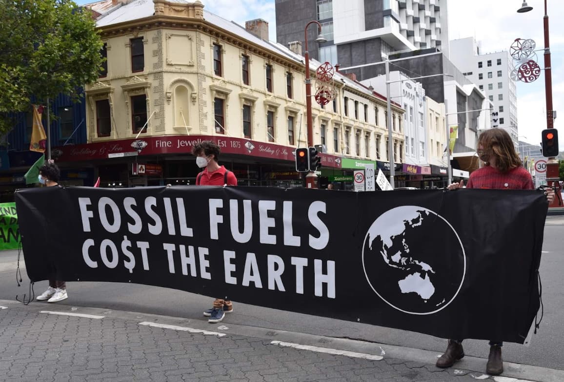 XR rebels in Hobart holding banner reading 'fossil fuels co$t the earth'