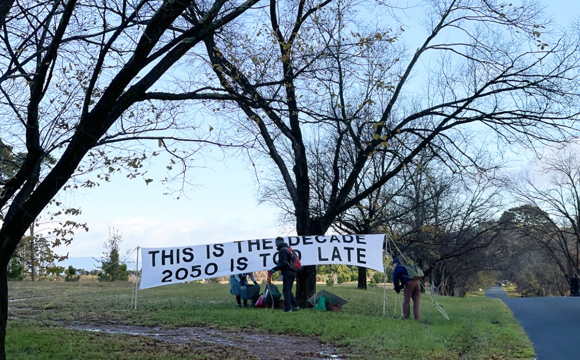 Protesters holding banner near the road to Government House in Canberra