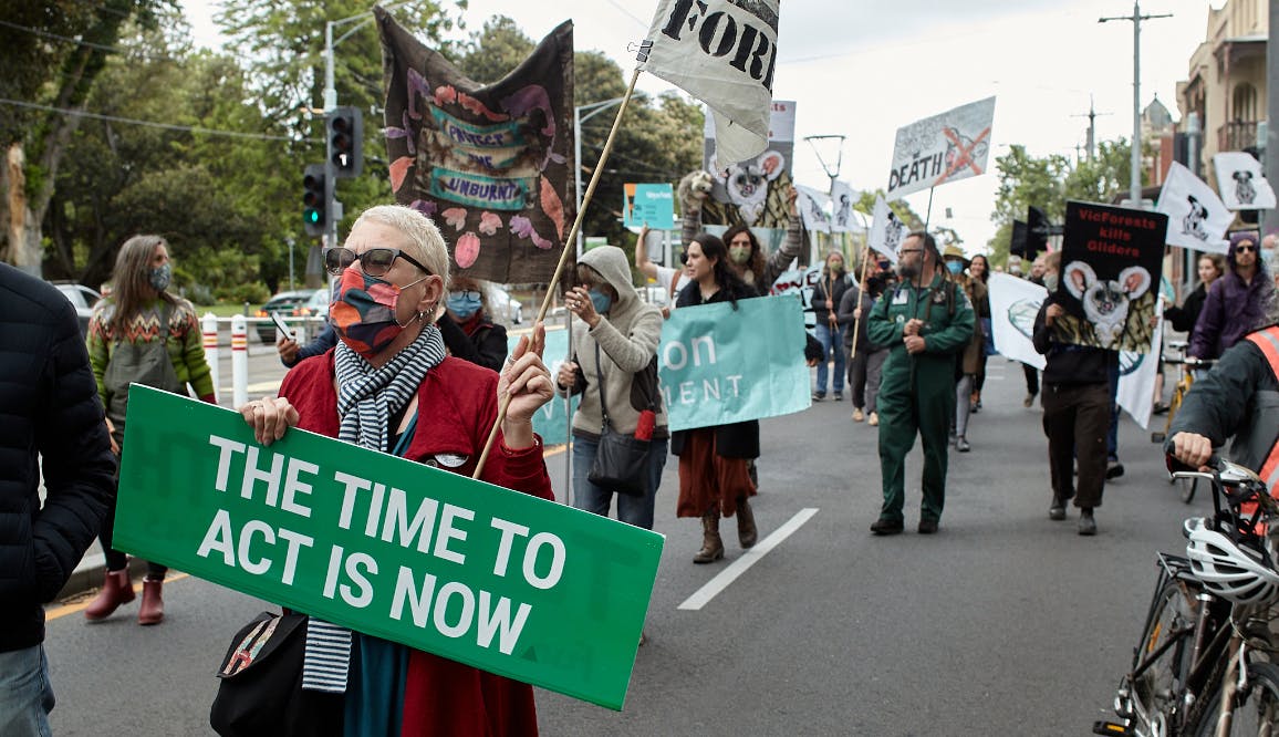 Extinction Rebellion Protester holding sign 'The time to act is now'