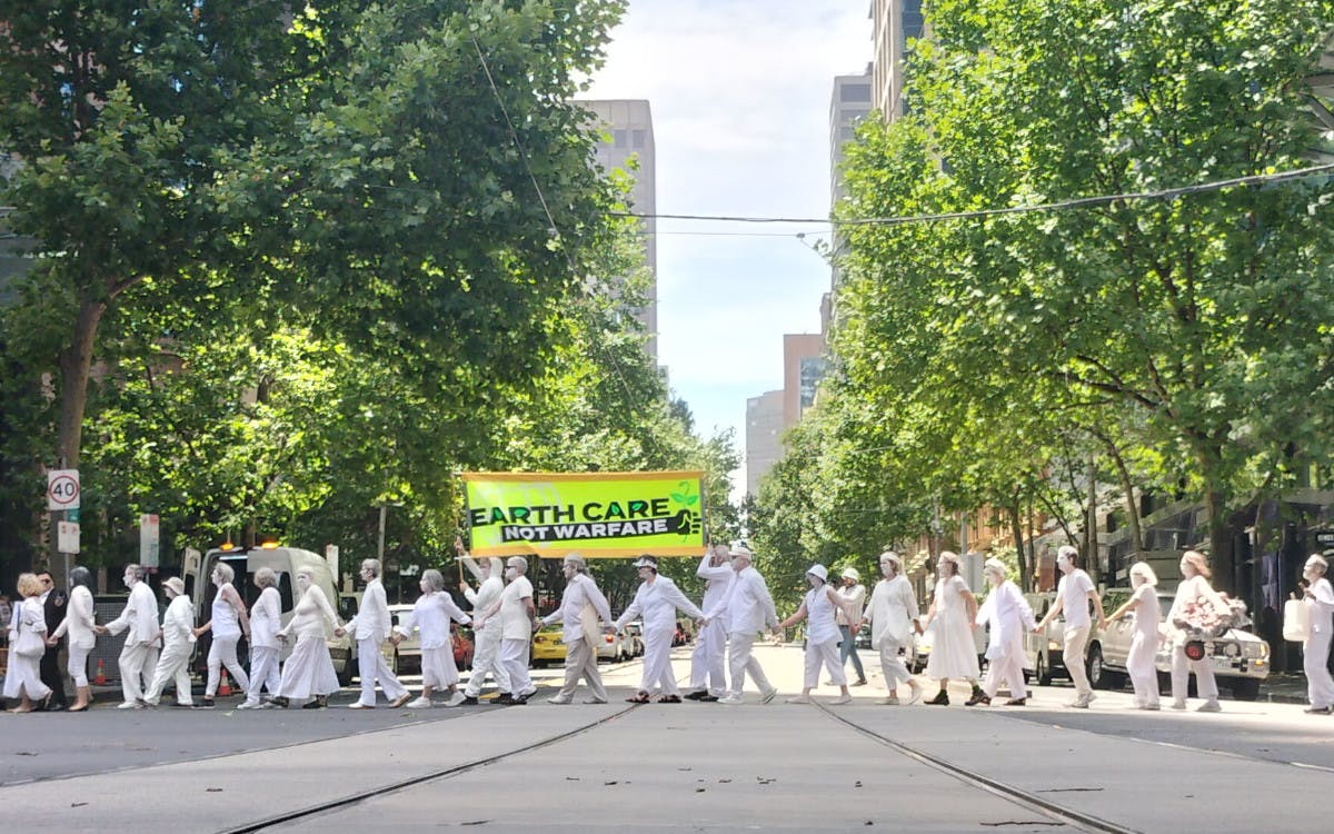 Rebels in white walk through the CBD in a human chain during the Earth Care not Warfare action