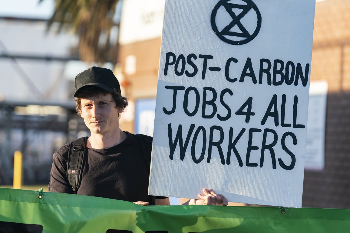 XR Protester holds sign reading 'Post Carbon Jobs 4 All Workers'