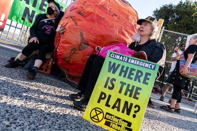 Extinction Rebellion rebels attach themselves to a huge representing of a burning Earth.