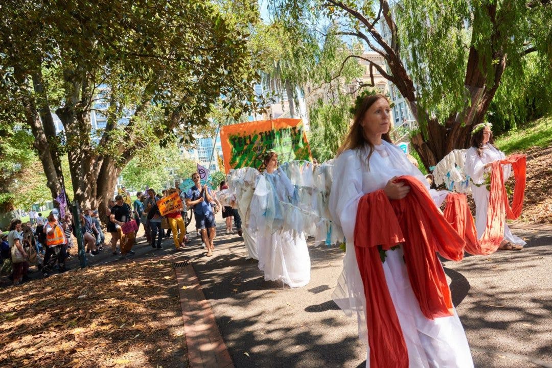 Photograph of activists in costume as the “Climate Angels” leading a group of activists through Treasury Gardens