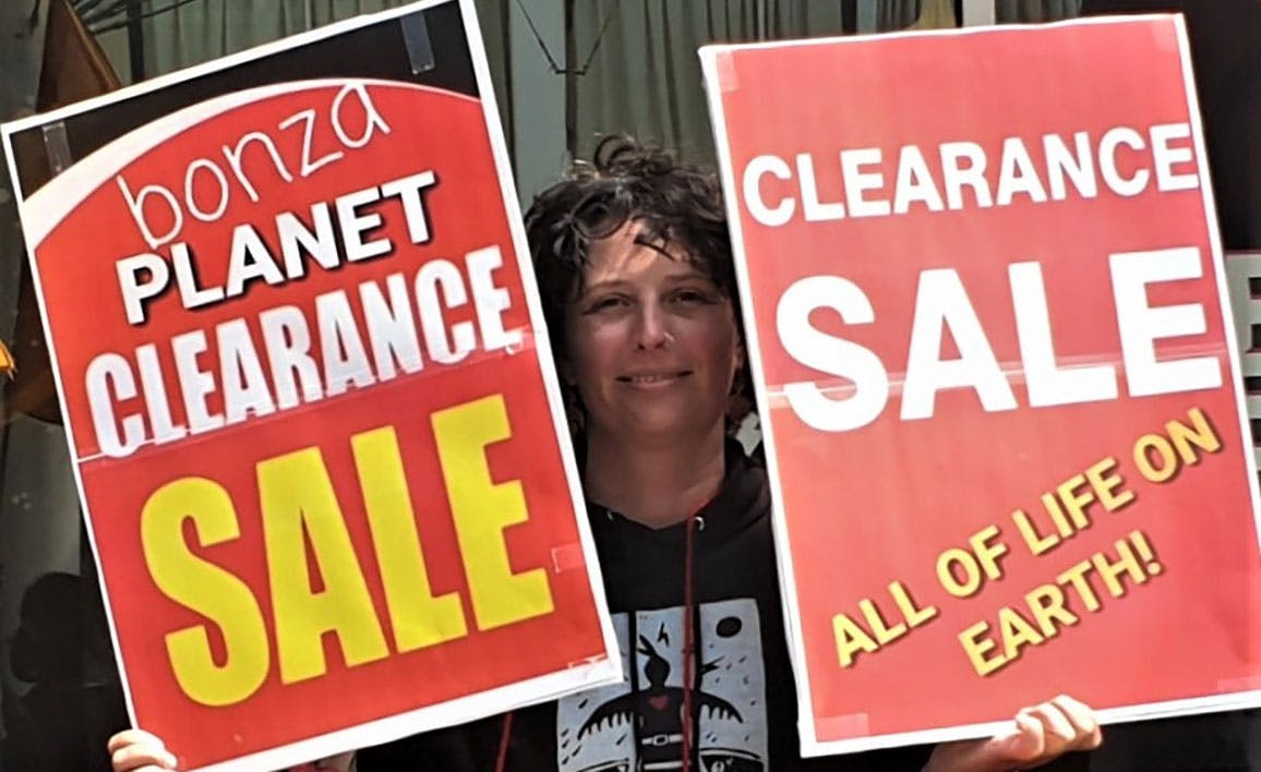 Two women with placards reading 'bonza planet clearance sale' and 'clearance sale all life on earth'