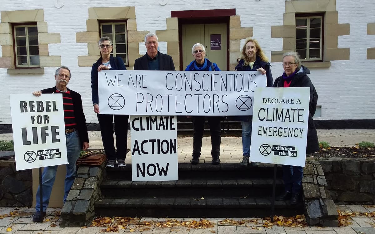 Jeff and XR Tas supporters outside court holding banners and placards