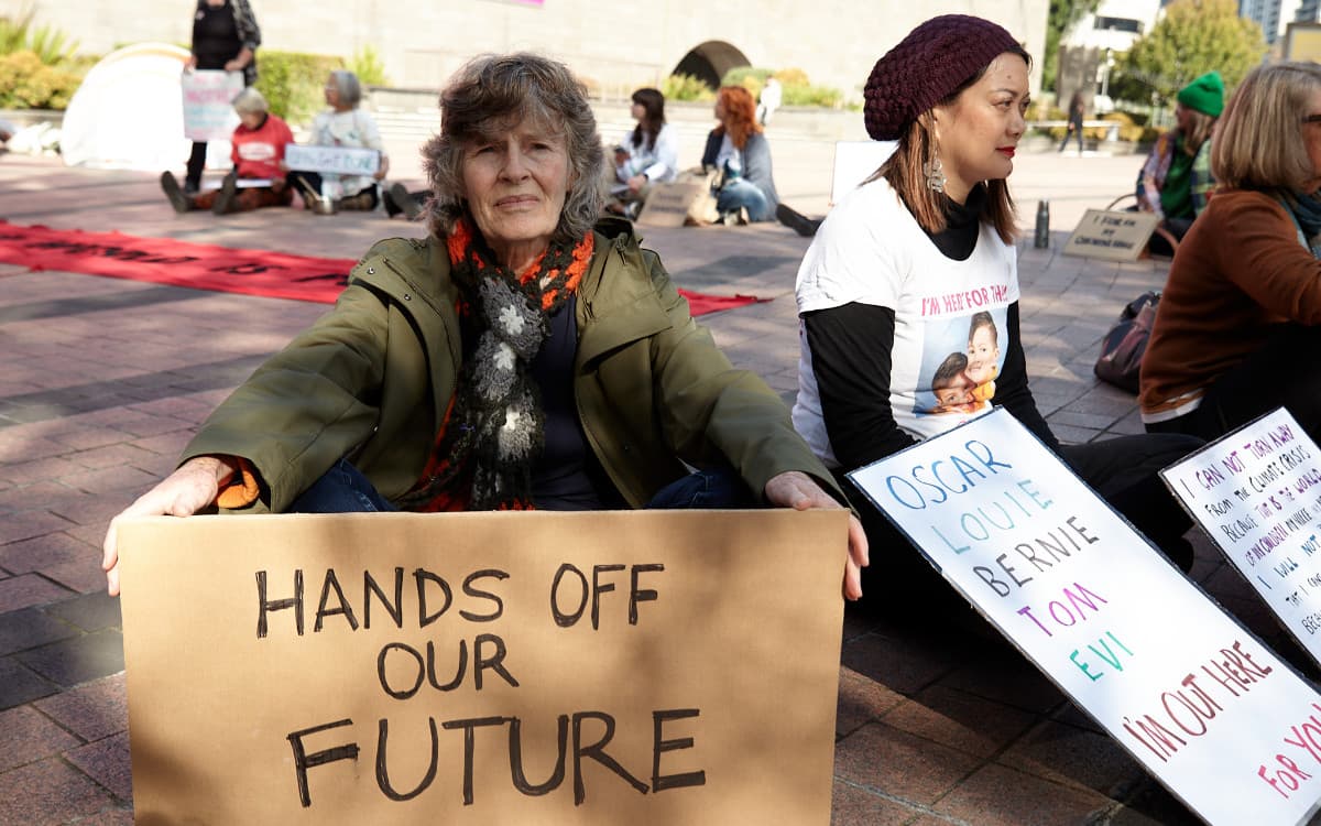 Women holding signs with names of children