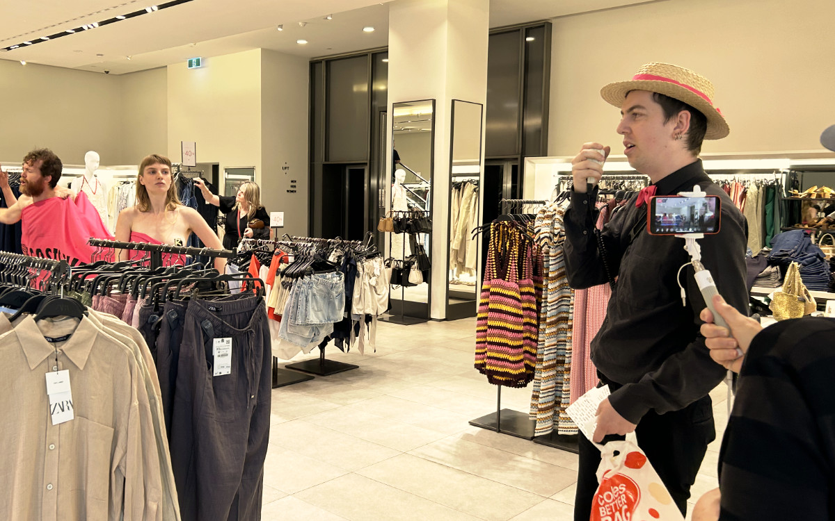 Inside a clothing store: spruiker Tim speaking into a microphone