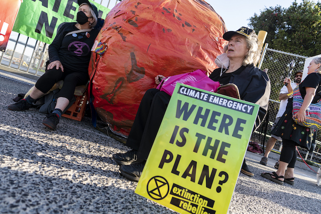 Extinction Rebellion rebels attach themselves to a huge representing of a burning Earth.