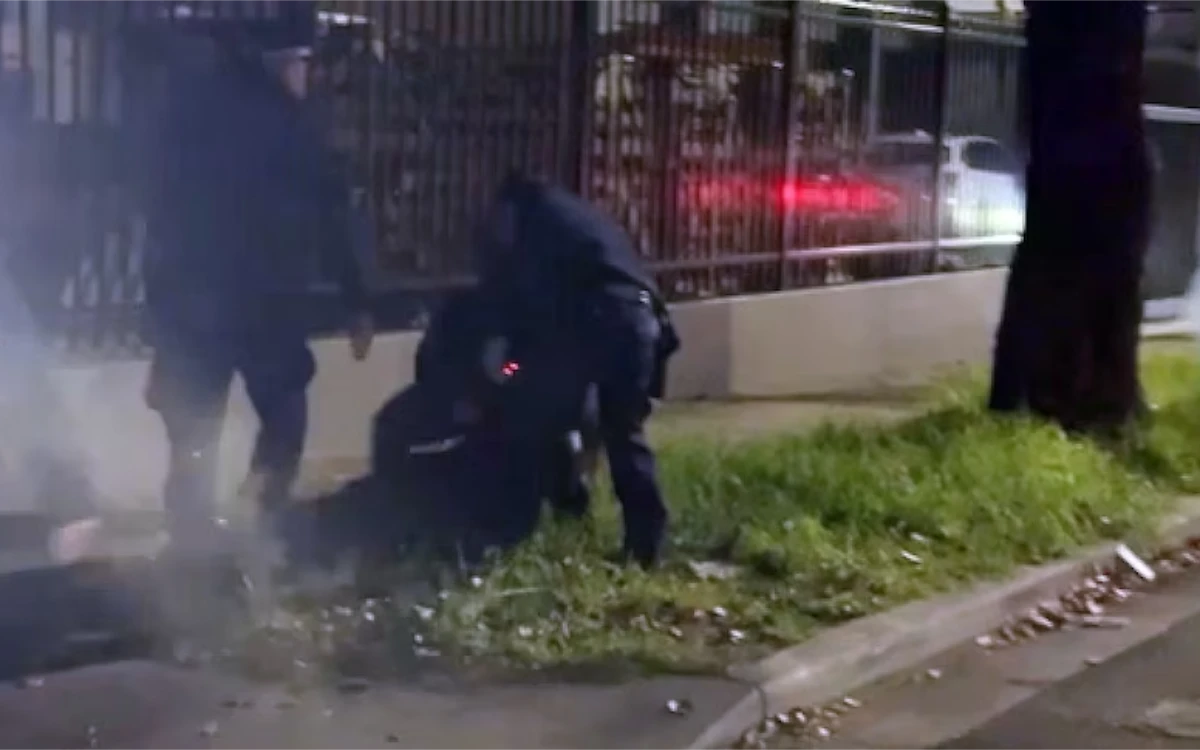 Dimly-lit street scene showing someone being dragged along the ground