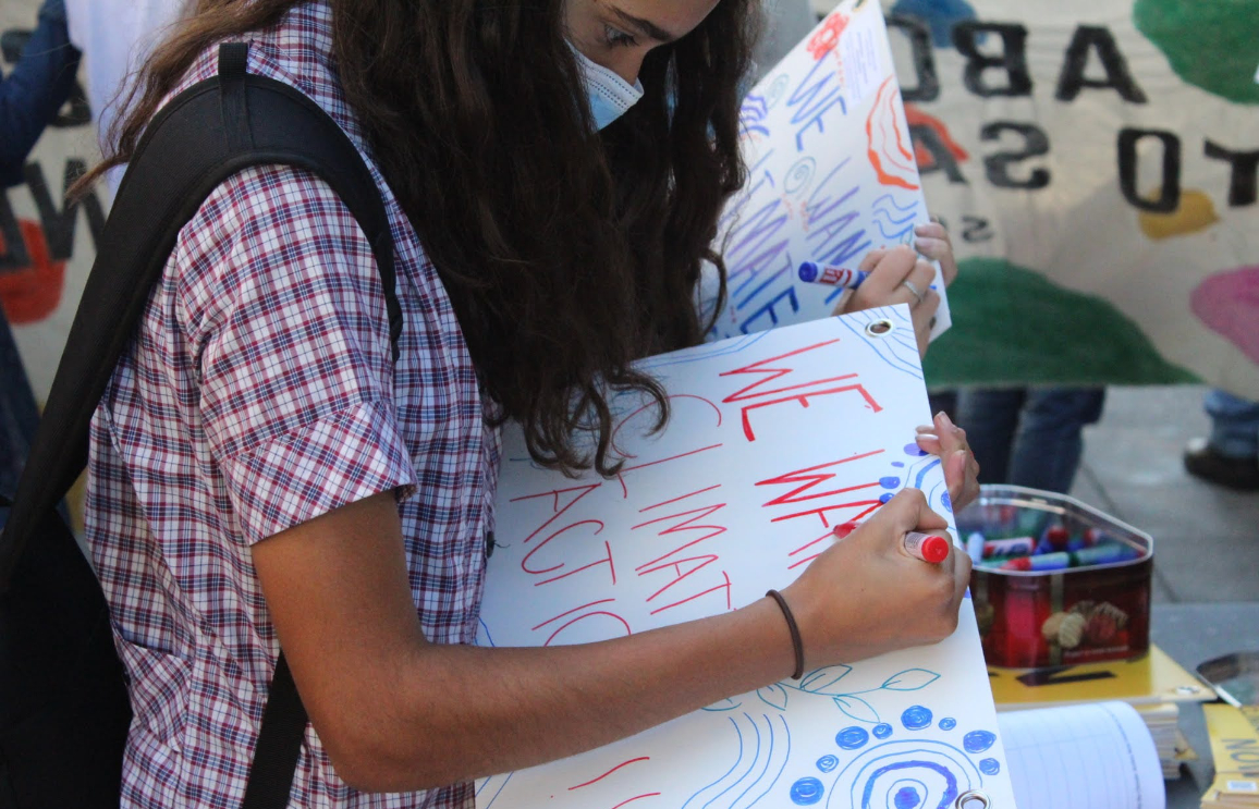 Student writing placard at the SS4C rally
