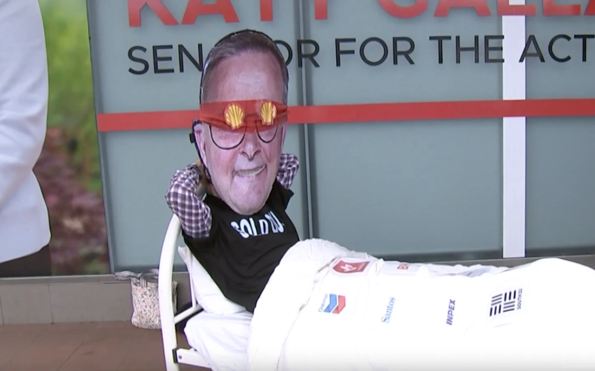 An activist with an Albanese face mask outside MP Katy Gallagher's office