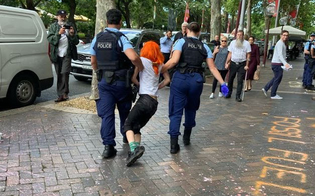 Police officers dragging Mai away down the street